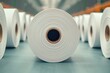 © Naree - A close-up view of a roll of paper, showcasing its texture and layers, surrounded by other similar rolls in a well-lit industrial setting.
