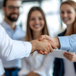 © cinta - Business Handshake: A close-up view of a successful handshake between two business professionals, symbolizing trust, collaboration, and a shared vision.  The blurred background depicts their team.