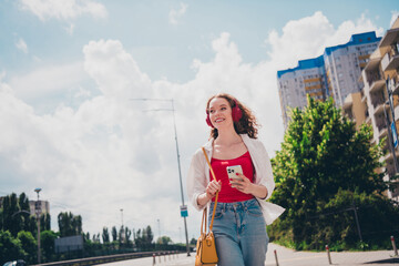 Poster - Photo of cheerful cute adorable girl headphones listen music walking wear white shirt enjoying free time sunny weather outdoors modern city