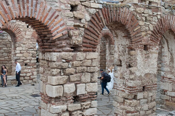 Blurred background. Wedding ceremony in old ruined fortress. Photo session, photographer with camera. Bride in white dress