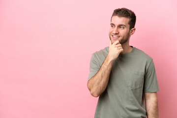 Wall Mural - Young caucasian man isolated on pink background looking to the side and smiling