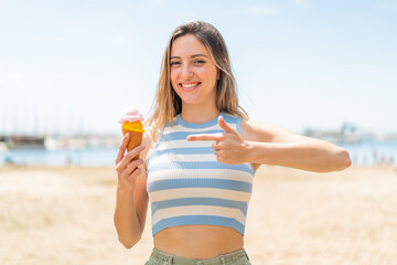 Poster - Young pretty woman with a cornet ice cream at outdoors and pointing it