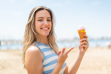 Poster - Young pretty woman with a cornet ice cream at outdoors and pointing it