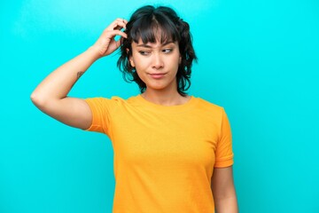 Wall Mural - Young Argentinian woman isolated on blue background having doubts while scratching head