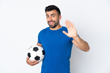 Handsome young football player man over isolated wall saluting with hand with happy expression