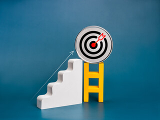 Wall Mural - Round metal target icon on top of minimal yellow ladder near arrow and white staircase as bar graph steps on blue background. Business goal and success, growth process, profit, investment concepts.