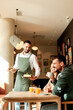 © BGStock72 - Waiter serves delicious vegetarian dishes to cheerful diners in a vibrant café during a sunny afternoon