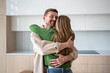 © DimaBerlin - Happy married couple embraces, feeling joy of achieving shared dream by move into new home. Loving man hugging woman celebrating start of new chapter together with purchase apartment in mortgage.