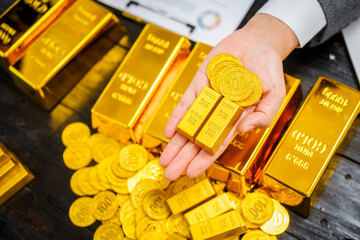 Businessman in suit sits at his desk, holding a shining gold bar. financial charts, the scene symbolizes wealth, investment success, growing influence of cryptocurrency and blockchain.