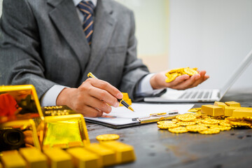 Businessman in suit sits at his desk, holding a shining gold bar. financial charts, the scene symbolizes wealth, investment success, growing influence of cryptocurrency and blockchain.