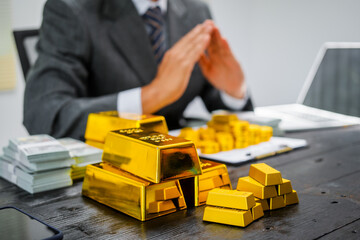 Businessman in suit sits at his desk, holding a shining gold bar. financial charts, the scene symbolizes wealth, investment success, growing influence of cryptocurrency and blockchain.