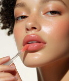 Young beautiful woman applying a lipgloss