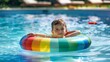 © liliyabatyrova - A young boy is floating in a pool with a rainbow inflatable ring