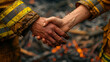 © Alina Tymofieieva - Two firefighters shake hands, showing camaraderie after successfully battling a wildfire in a forest.