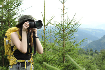 Canvas Print - Young hiker with backpack and camera in forest, space for text