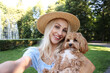© New Africa - Beautiful young woman taking selfie with cute dog in park