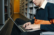 © DragonImages - Student typing on laptop and doing online work while sitting in the library