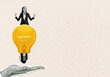 © Who is Danny - Businesswoman standing on a lightbulb held by a hand, with a blank background for copy space.