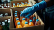 © Prasanth - A person wearing blue gloves is reaching into a box of juice bottles
