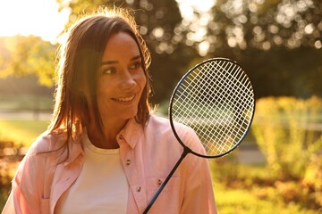 Poster - Happy young woman with badminton racket in park on sunny day