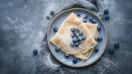 Canvas Print - A visually appealing plate of crepes garnished with powdered sugar and fresh blueberries, placed on a rustic surface.