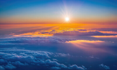 A golden sunset shines through the clouds as seen from above