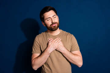 Sticker - Photo of grateful man with stylish beard haircut dressed beige t-shirt holding arms on chest isolated on dark blue color background