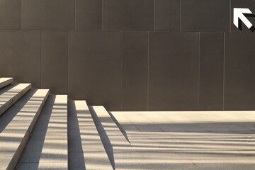 Stairs and Shadows.  Dark wall. The interplay of geometry, light, and shadow. Black wall of the building and light stairs	