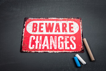Wall Mural - changes. beware sign with text and colored pieces of chalk on a dark chalkboard background