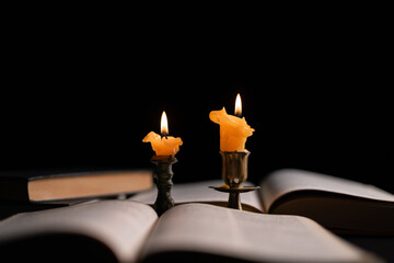 Dark, an antique candle cast its light on the old Bible, its flames flickering gently over the book on the table, symbolizing the enduring essence of religion. candle, bible, dark, light, book, old.