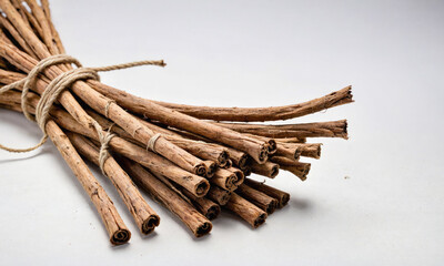 A bundle of cinnamon sticks tied with twine sits on a white background