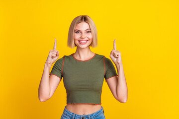 Sticker - Photo of positive adorable girl with bob hairstyle dressed khaki t-shirt directing at logo empty space isolated on yellow color background