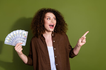 Wall Mural - Photo of pretty young woman hold cash direct finger empty space wear brown shirt isolated on khaki color background