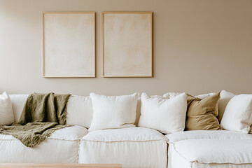 Wall Mural - Two large blank wall frames hanging above the sofa in the living room, a cream and beige color scheme, a white couch with multiple pillows and throw blankets and soft natural lighting.