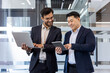 © Liubomir - Two male professionals in business attire discussing project details using laptop and tablet. Conveying teamwork, communication, and technology in workplace. Ideal for concepts of collaboration