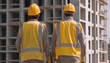 © javu - Construction workers observing a building site, equipment in background.
