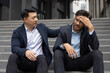 © Liubomir - Business professional offering support to stressed colleague. Two men sit on office steps, one providing empathy and understanding during challenging work situation. Concept of support.