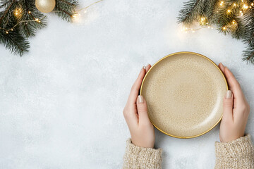 
top view femle hands, holding a golden empty plate in a festive setting,