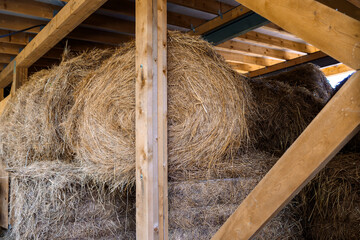 Stacked bales of hay lie in storage in barn. Rural organic nature farm