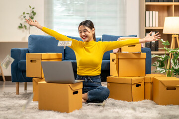 A woman in a yellow shirt is sitting on the floor surrounded by cardboard boxes