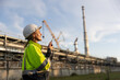 © naraichal - A top-notch female chemical supervisor, making sure the plans are on track by using radio communication with the team and her laptop at the oil refinery.