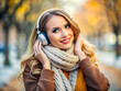 © Ольга - A cheerful young woman with a scarf and headphones, enjoying music in a fall setting, with a warm smile as she stands in a park filled with autumn colors