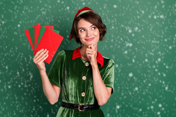 Wall Mural - Portrait of attractive cheery minded girl thinking holding letters choosing copy space isolated over green color background