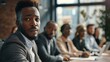 © Tanakrit - A focused man in a suit looks back at a group conversing in a modern office setting, showcasing engagement in a professional environment.