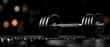 © Chanagun - A sleek, black dumbbell rests on a reflective surface, surrounded by soft bokeh lights, symbolizing strength and fitness.