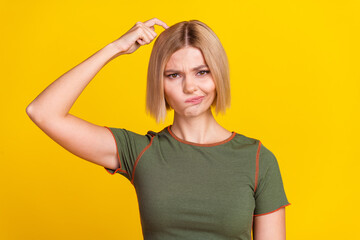 Poster - Photo of suspicious puzzled girl with bob hairstyle dressed khaki t-shirt finger scratching head isolated on yellow color background