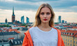 © Miklos - A young woman stands with a cityscape behind her, a warm, overcast sky above