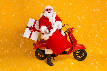 Sticker - Full body profile side photo of grey white hair bearded santa claus sit scooter put gift box in sack wear red headwear sunglass boots isolated bright shine color background