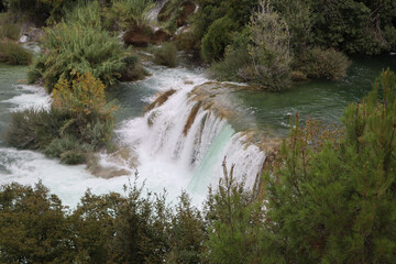 Picturesque waterfall on a river with emerald green water,  the Krka River on a autumn day