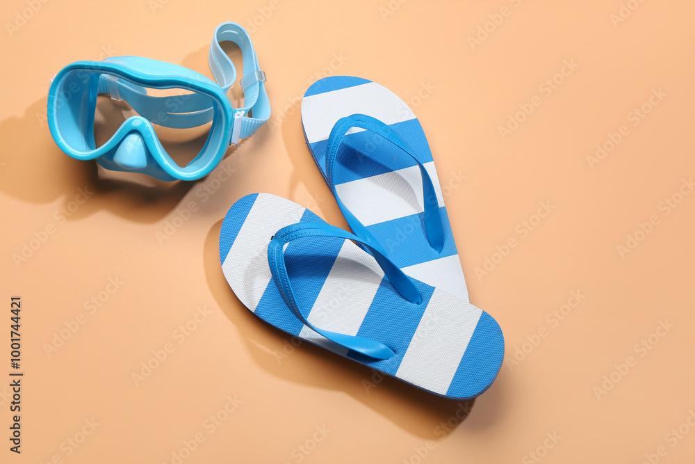 Female stylish flip flops with snorkeling mask on orange background